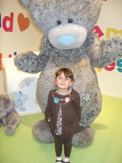 A large brown teddy bear sitting on top of a stuffed toy