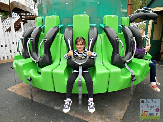 A person sitting on a bench in front of a green toy