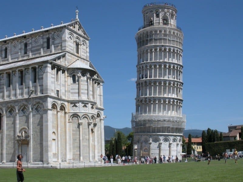 A group of people standing in front of a large building with Leaning Tower of Pisa in the background