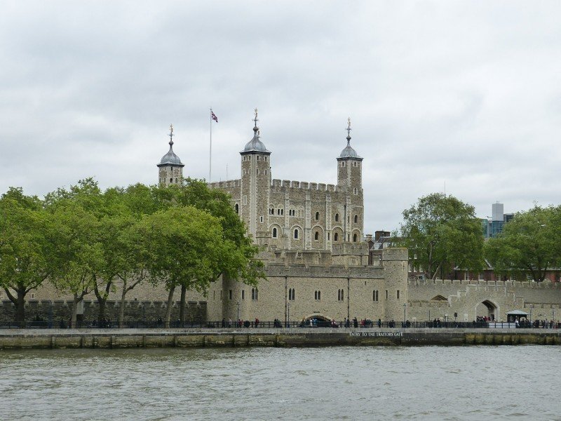 A castle with water in front of a body of water with Tower of London in the background