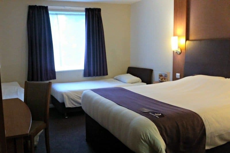 A bedroom with a bed and desk in a hotel room
