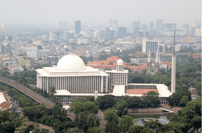 A large body of water with Istiqlal Mosque, Jakarta in the background