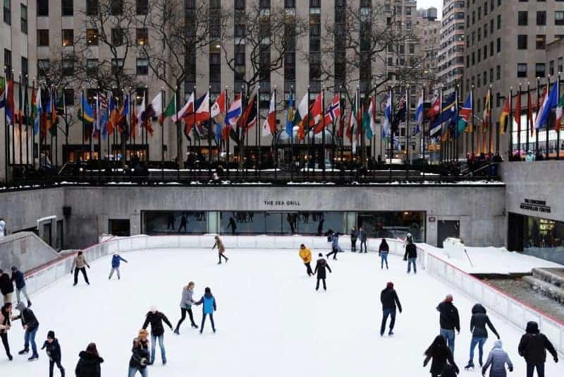 A group of people riding skis on top of Rockefeller Center