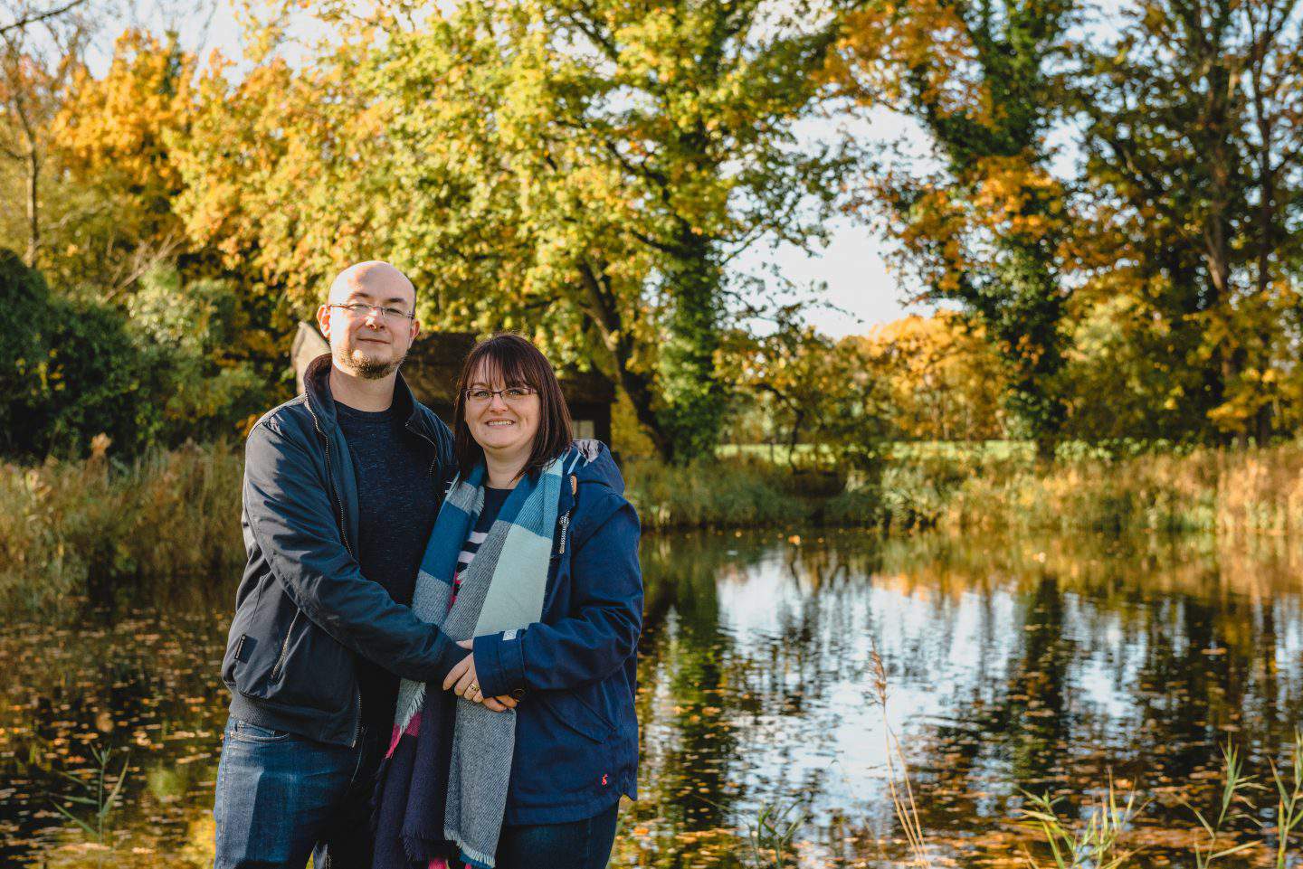 A person standing next to a lake, with Beth Moseley Photography