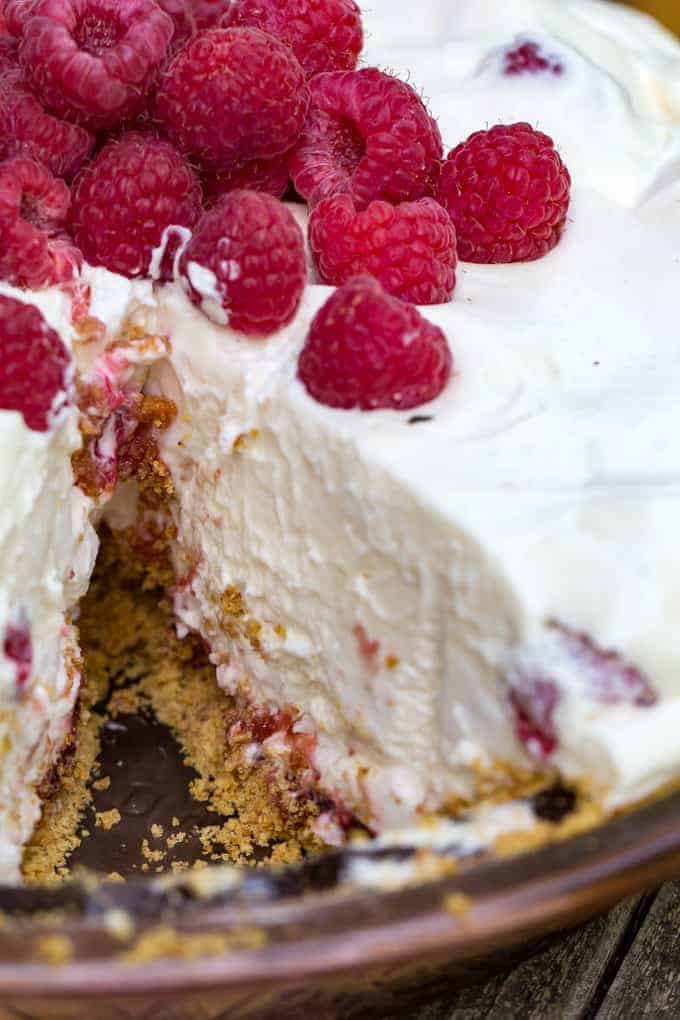 A close up of a piece of cake and ice cream on a plate, with Cheesecake and Raspberry