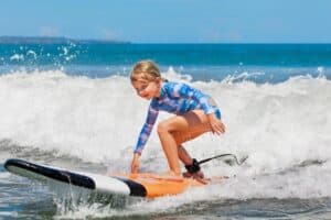 A young girl riding a wave on a surfboard in the water