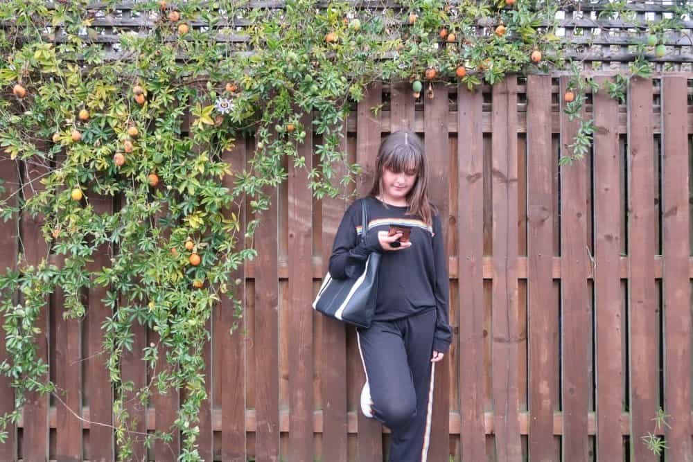 A woman sitting on a bench in front of a wooden fence