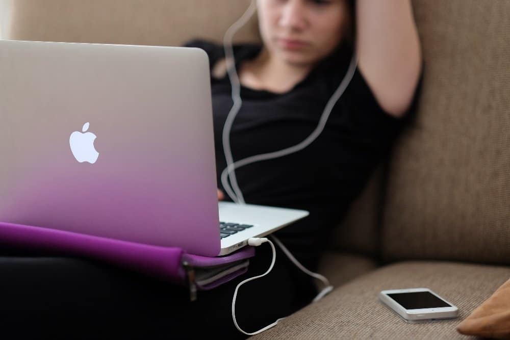 Mental health of teens - teen sitting on sofa with MacBook