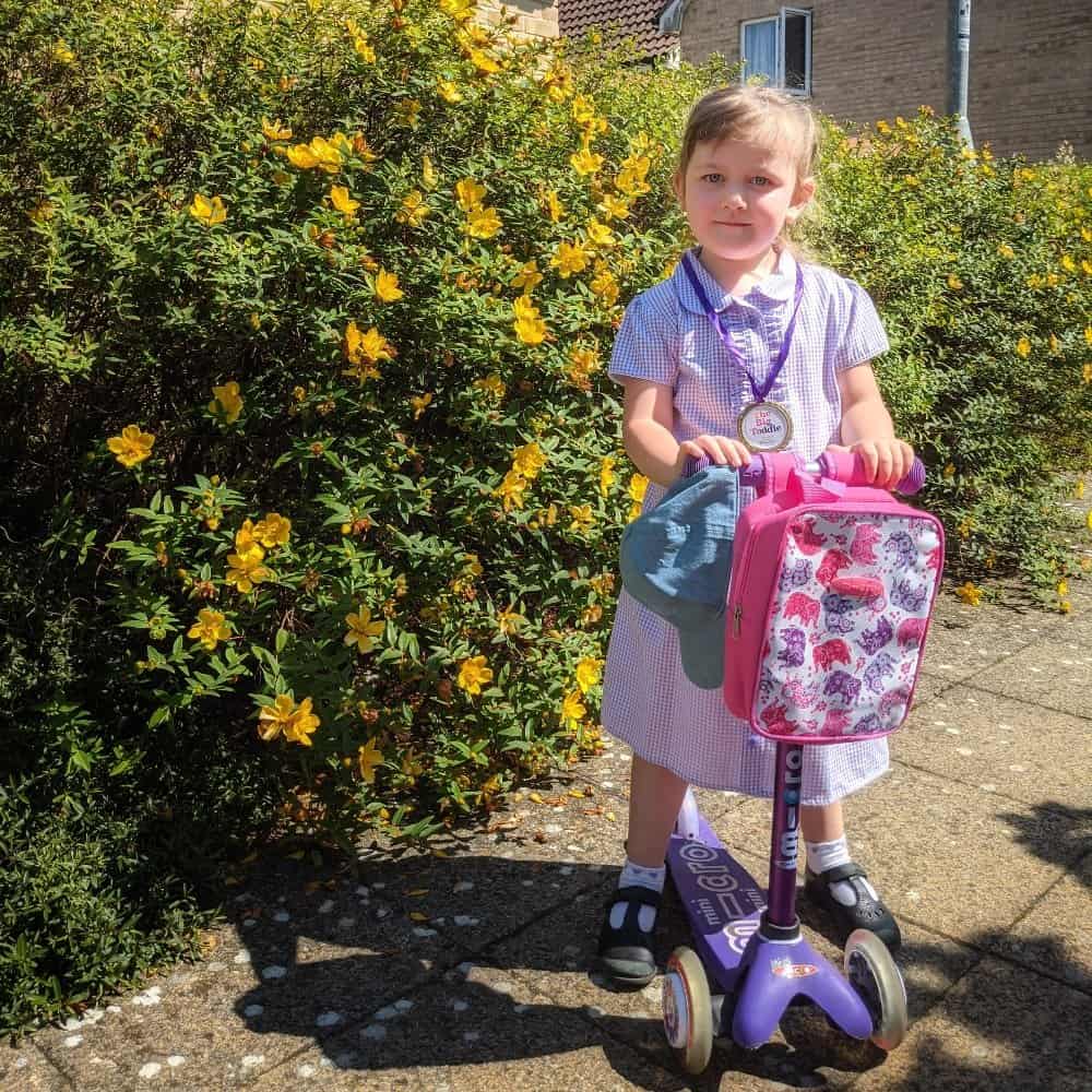 Life In Lockdown | Back to preschool
child standing with a purple micro scooter in front of a green bush