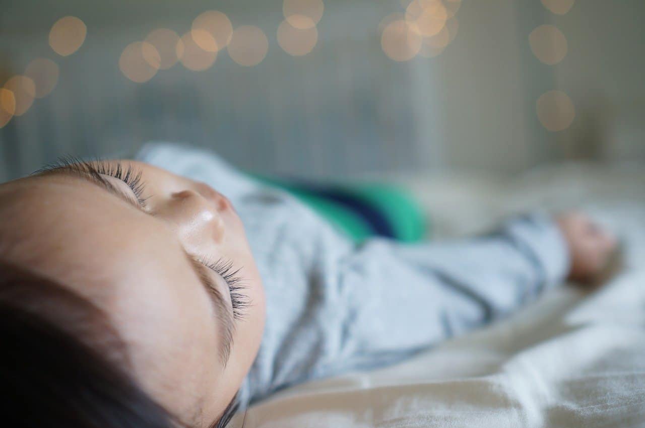 A close up of a baby lying on a bed