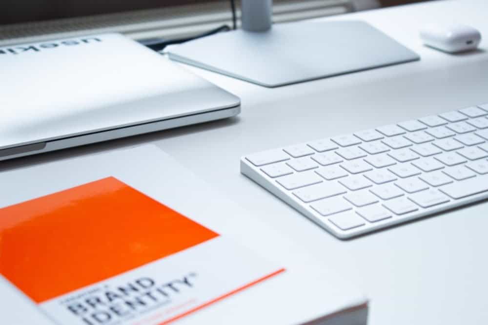 How to create graphics for your blog -brand identity book on a white desk with apple keyboard