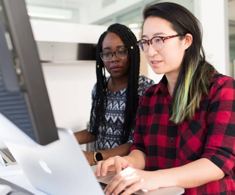 woman wearing red and black checkered blouse using macbook