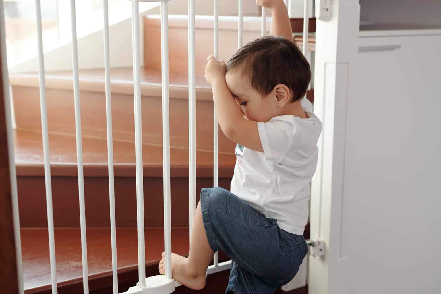 Babyproof your house to ensure safety and freedom - little boy trying to climb up a stair gate