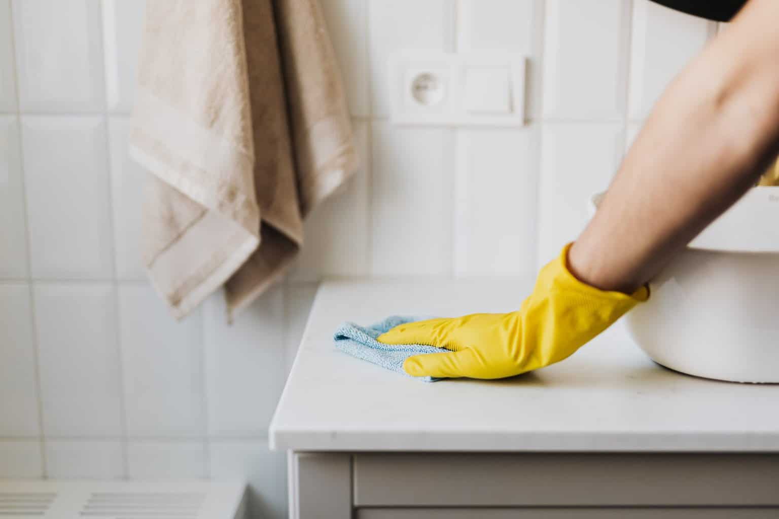 crop housewife cleaning surface near a bathroom sink - How to Clean Your Bathroom in 15 Minutes