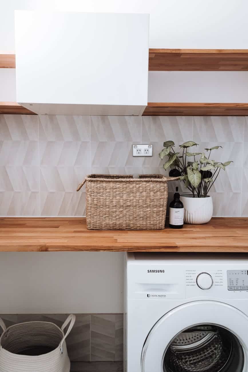 washing machine under wooden table with plant and wicker basket - Simple Things Everyone Can Do To Save The Environment