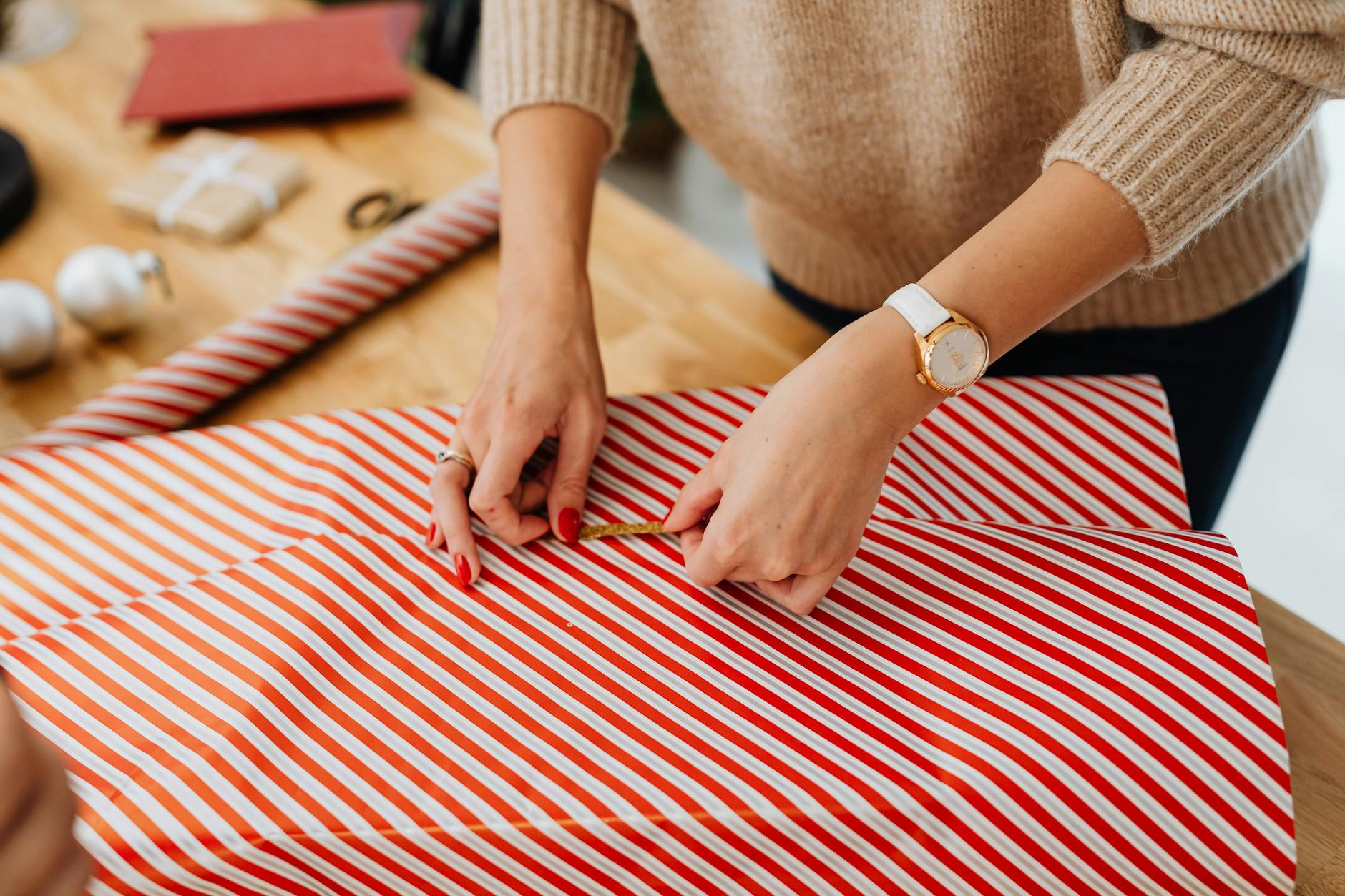 woman in brown sweater wrapping a gift